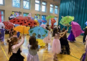 Uczniowie klas młodszych ubrani w stroje karnawałowe bawią się na szkolnym balu.