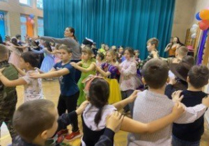 Uczniowie klas młodszych ubrani w stroje karnawałowe bawią się na szkolnym balu.