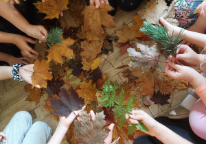 Uczestnicy zajęć świetlicowych oglądają liście różnych drzew.