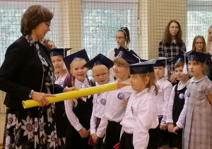 Pani dyrektor pasuje pierwszaki na uczniów dużym ołówkiem