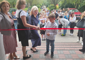 Przecięcie wstęgi do szkoły przez ucznia klasy pierwszej.