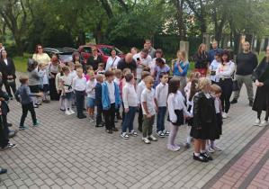 Powitanie uczniów klasy pierwszej przed budynkiem szkoły.