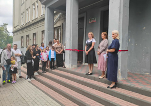Powitanie uczniów klasy pierwszej przed budynkiem szkoły.
