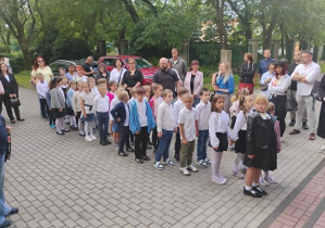 Powitanie uczniów klasy pierwszej przed budynkiem szkoły.