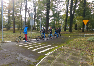 Grupa uczniów z rowerami oczekuje na polecenia egzaminatora.