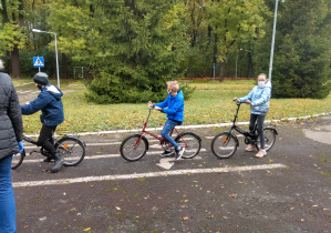 Troje uczniów na rowerach oczekuje na kolejne polecenia egzaminatora.