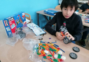 Uczeń konstruuje pojazd z klocków K'nex education.