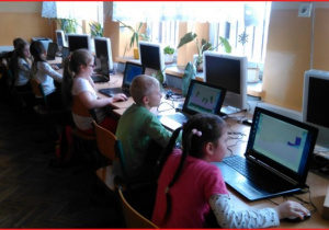 Uczniowie pracują na laptopach.